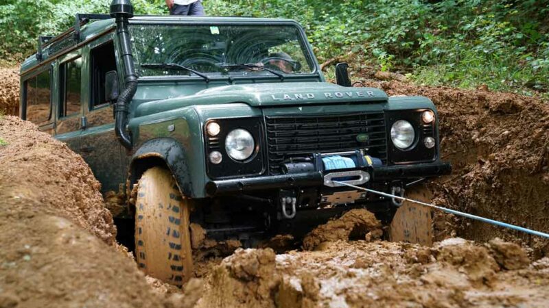 Land Rover im Offroad-Gelände, hängt an der Seilwinde und eine Bergeaktion ist im Gange.