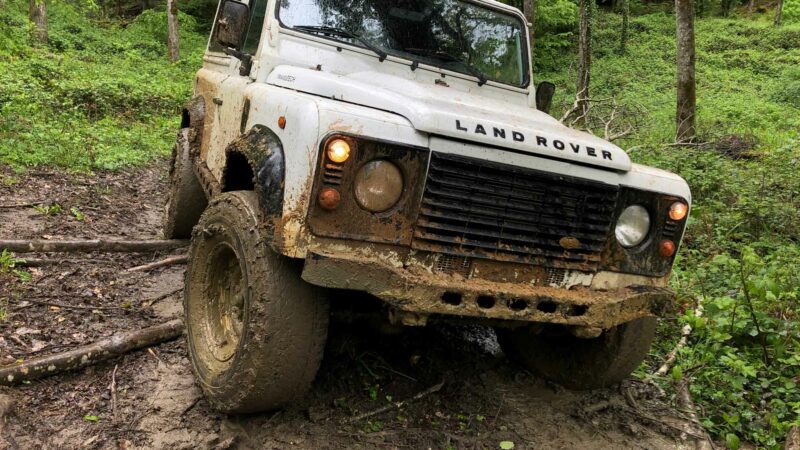 Schmutziger Land Rover Defender 90 im Offroad Gelände